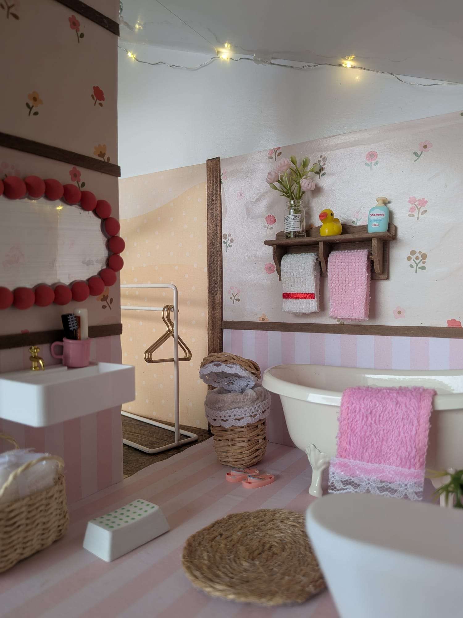 Pormenores da casa de banho em miniatura, com espelho, toalhas e luzes