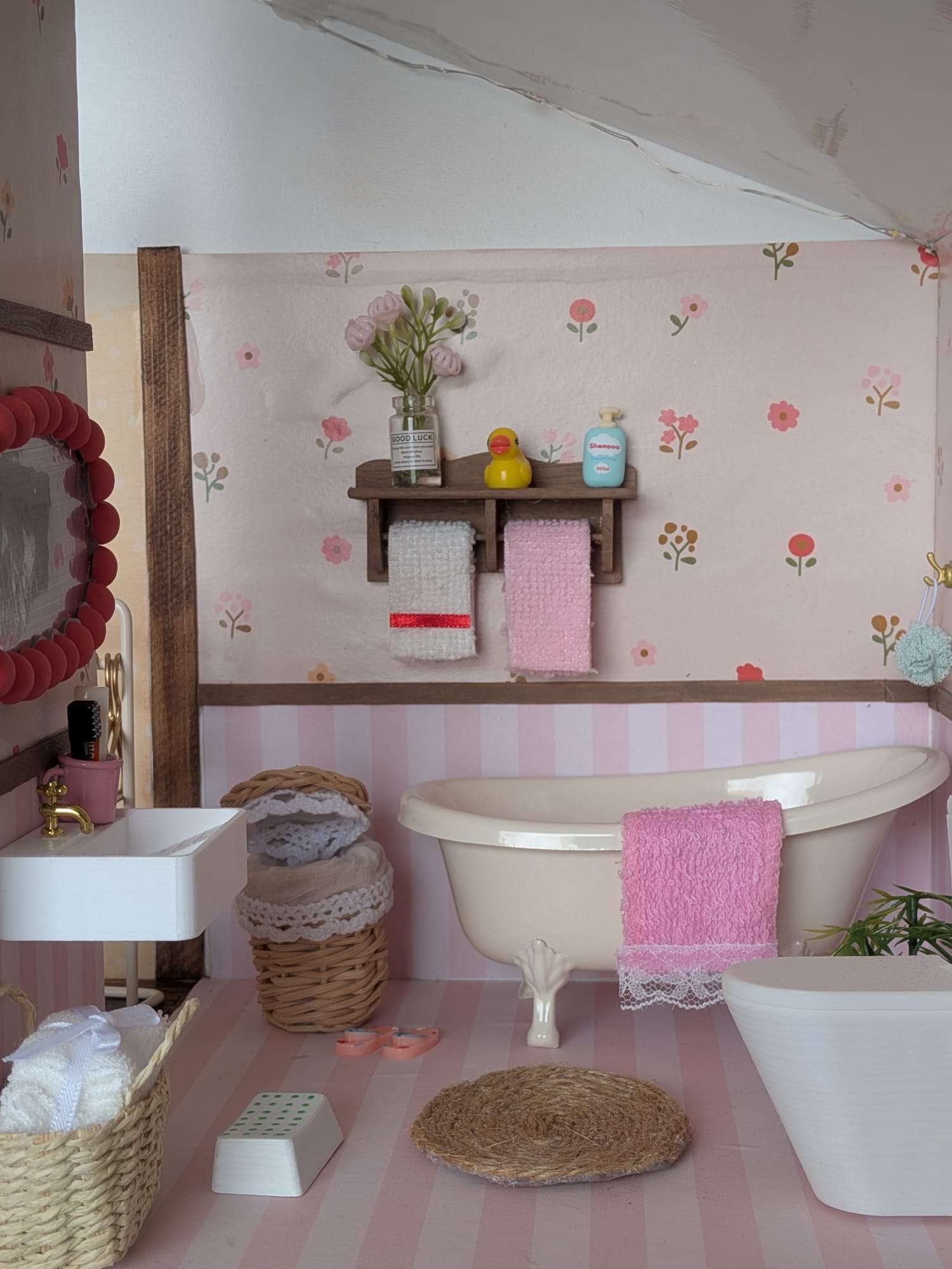 Casa de banho em miniatura rosa, com banheira e cestos