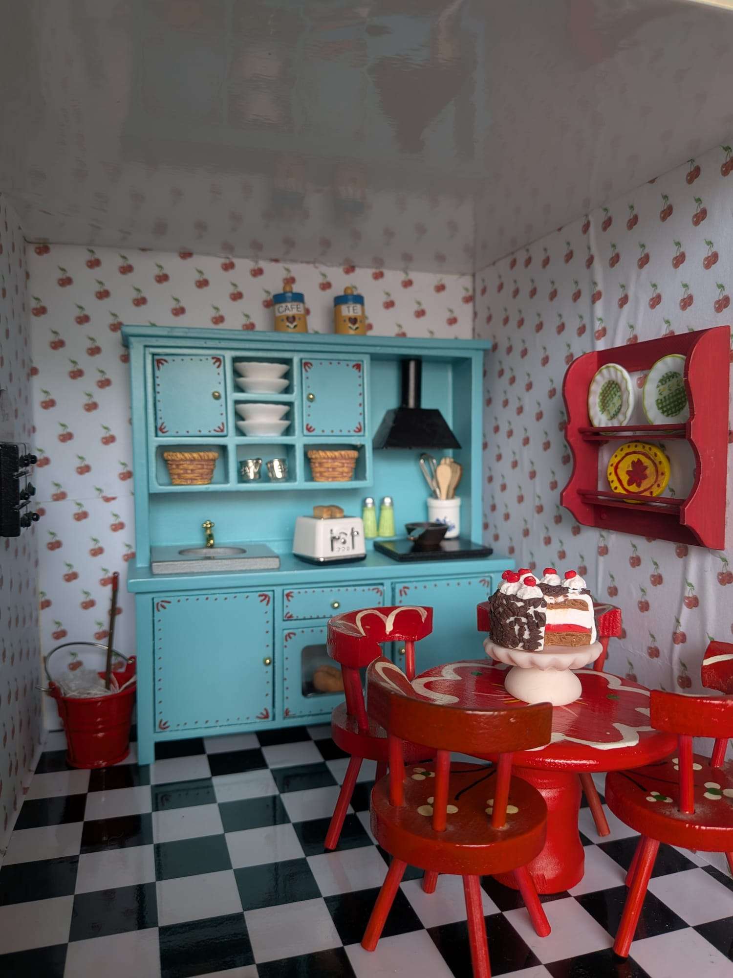 Cozinha em miniatura azul e vermelha, com mesa posta